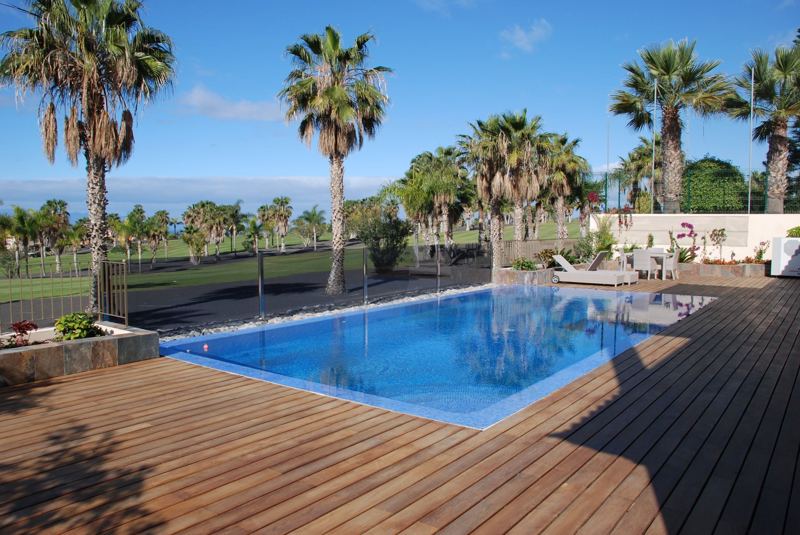 Piscina con deck de madera y palmeras