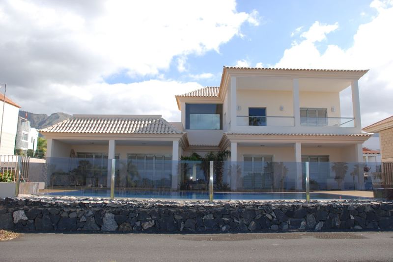 Vivienda con barandilla de vidrio y muro de piedra